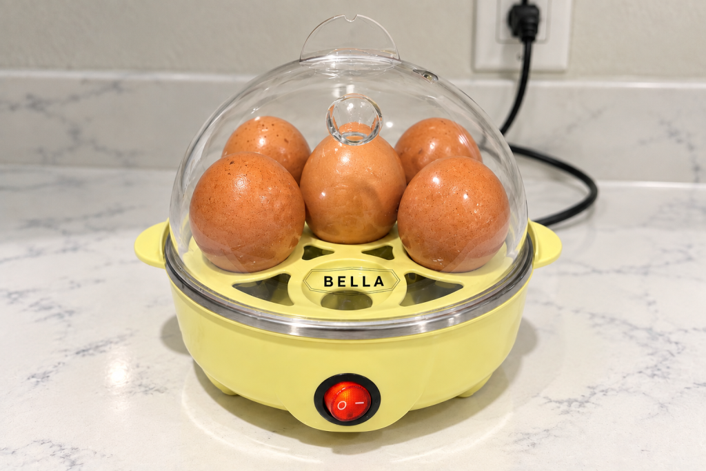 갈색 계란 5개를 넣고 사용 중인 노란색 BELLA 에그 쿠커